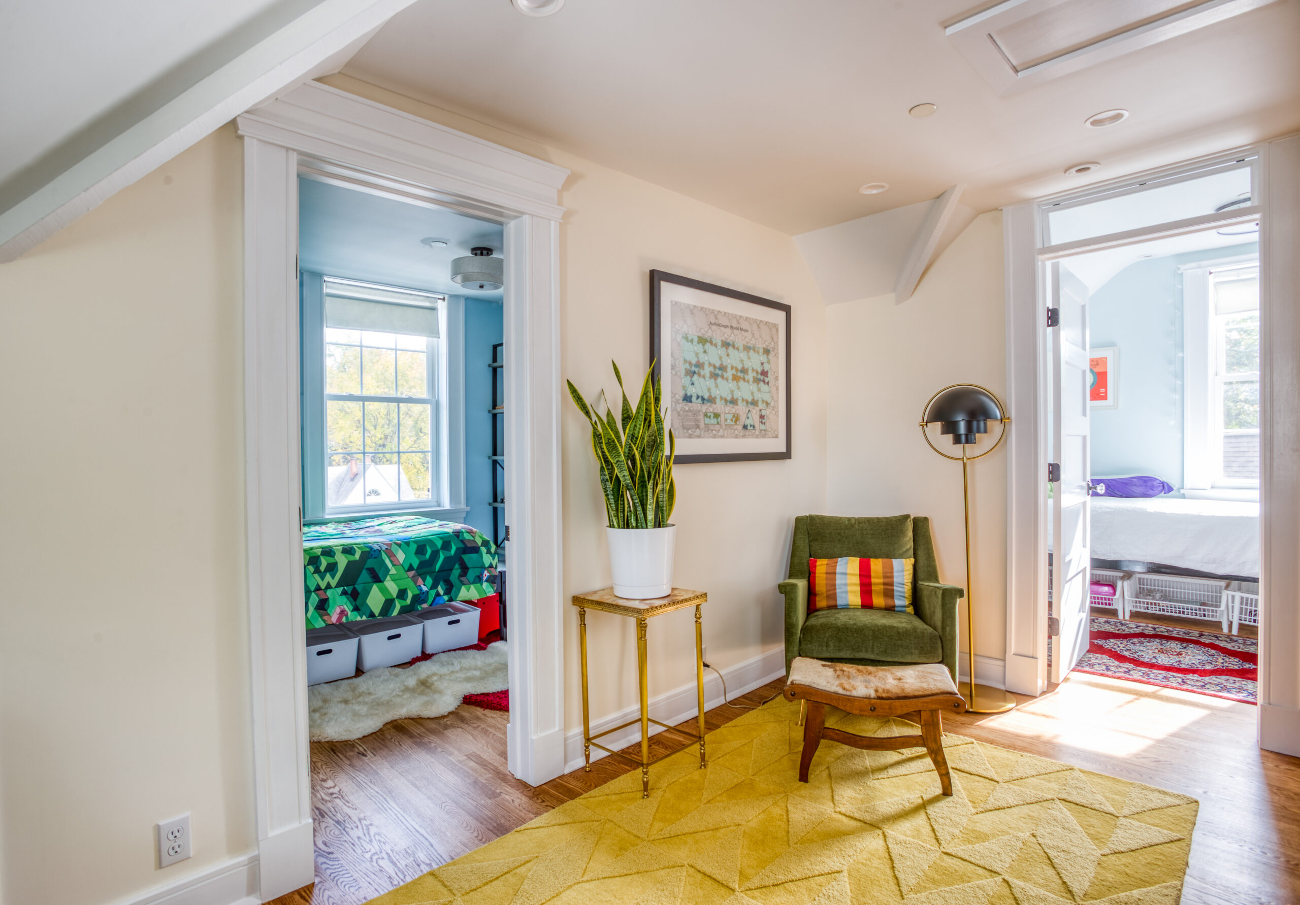 Updated top-floor hall linking kids’ bedrooms, sloped ceiling, and new trim, showing storage-minded planning in a finished attic renovation.