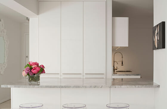 This marble-top island also took the place of a full wall, and the minimalist cabinetry was custom-designed by GSDO and made by Porcelanosa.