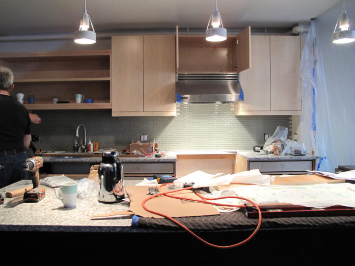 kitchen with island and pendant lights and cabinet installation in progress during renovation