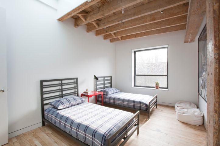 bedroom with wooden ceiling beams and hardwood floor and white walls after renovation