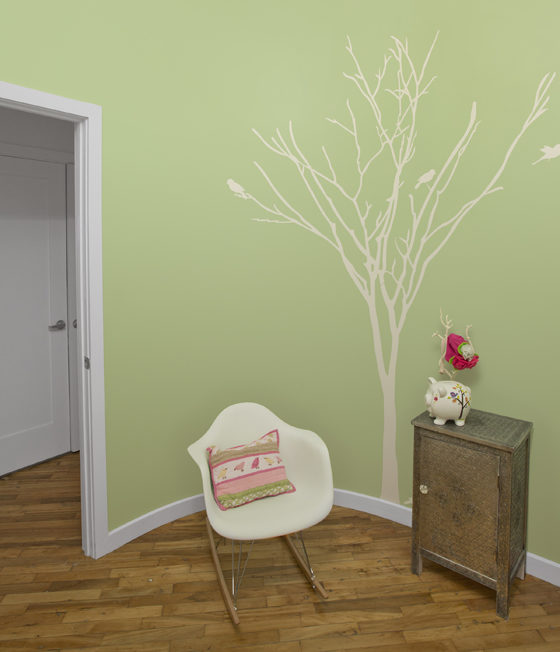 hand painted tree mural on a pastel green wall and shoe molding and hardwood floors after renovation