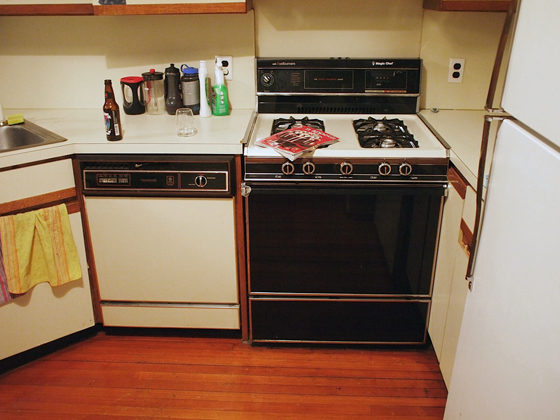 off-white cabinets with brown wood trim and old appliances and hardwood floor and before renovation