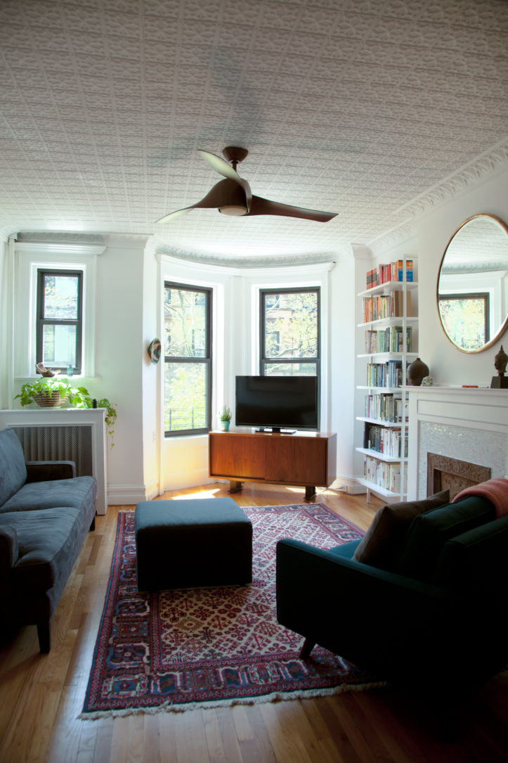 living room with a round corner and hardwood floors and fireplace and crown molding and tin ceiling tiles after renovation