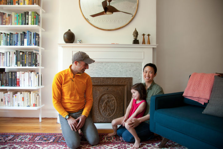 family sitting infront of fireplace and hardwood floors after renovation