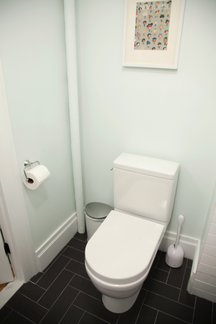 toilet with white walls and black tiles on floor and door after renovation