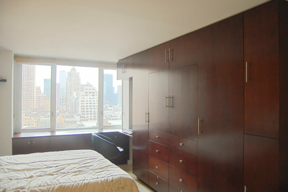bedroom with city view and window bench seat with storage and built in walnut wardrobe or cupboard with drawers after renovation