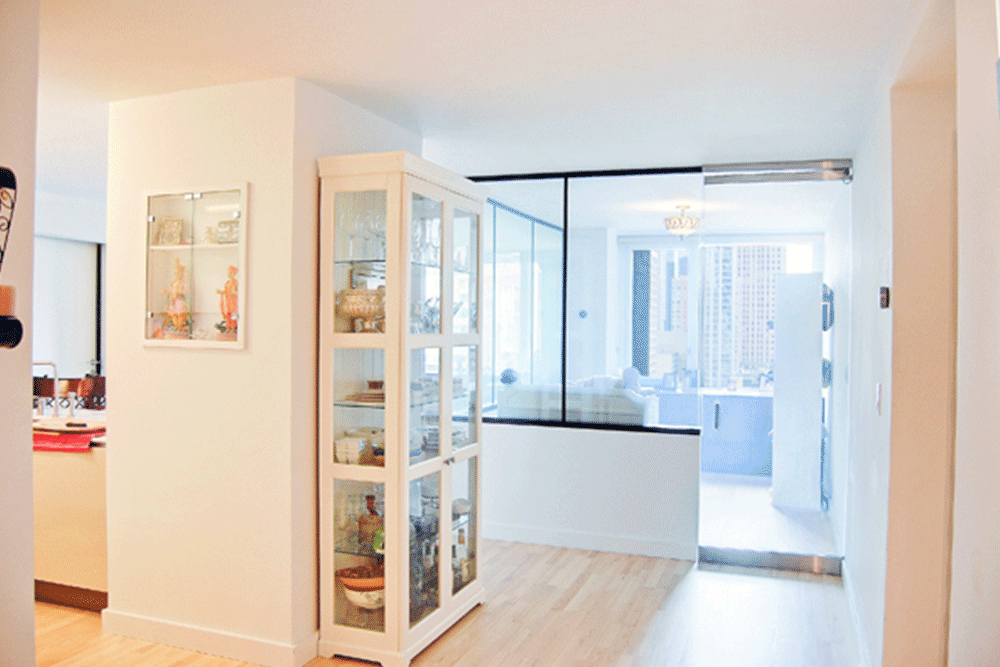 glass wall with black frames in a room and hallway with hardwood floors after renovation