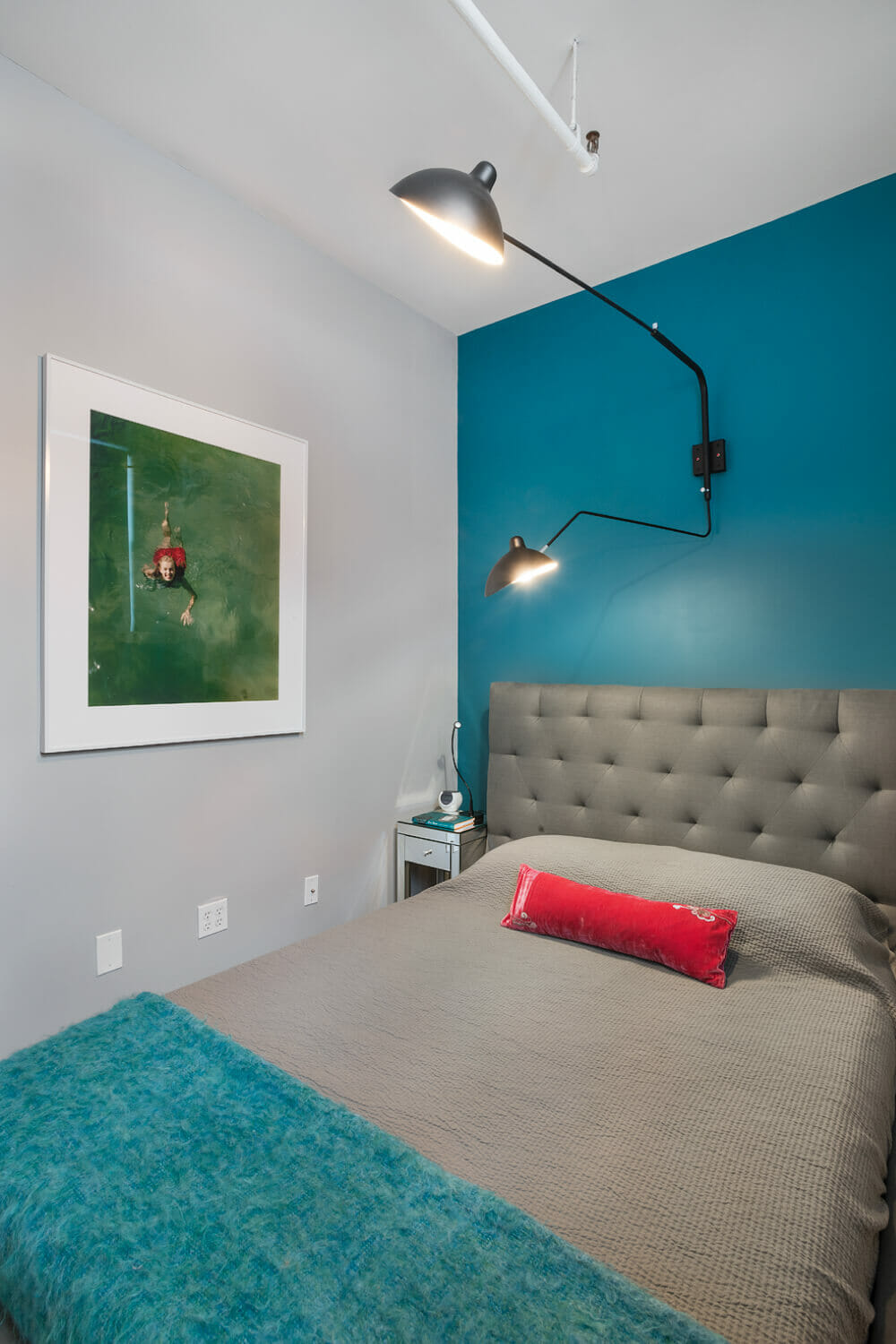bedroom with teal accent wall and adjustable long reach wall mounted lights after renovation