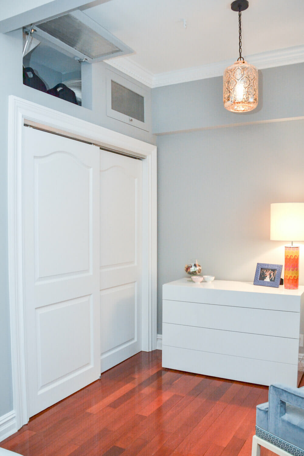 closet with sliding doors and overhead storage and pendant light and hardwood floor after renovation