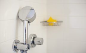 Close up of a chrome showerhead on white subway tile in a bathroom remodel in Murray Hill.
