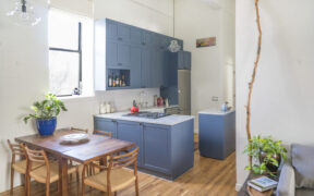 Park Slope kitchen with navy custom cabinets, a quartzite counter, white subway tile backsplash, high ceilings, and a movable island.