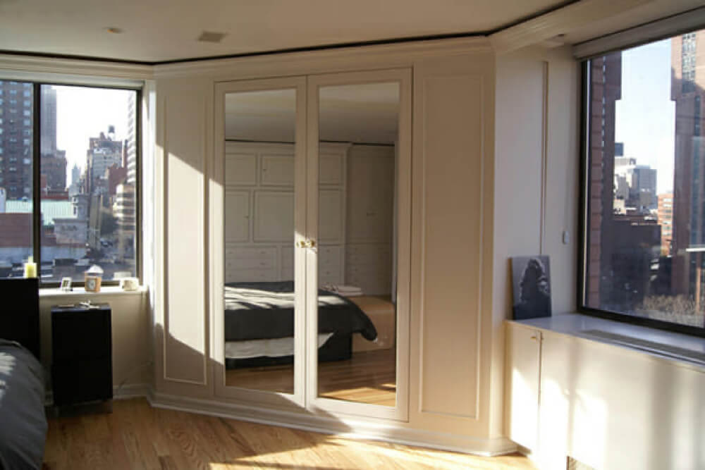bedroom with built in mirrored wardrobes and hardwood floors and window seating after renovation