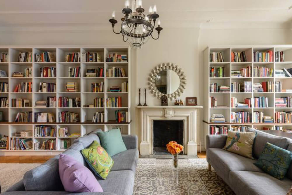 large built-in book shelves on either side of the fireplace in the living room with chandelier after renovation