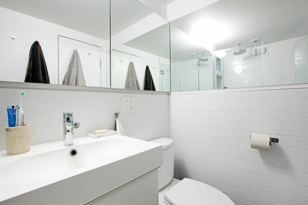 white bathroom with vanity mirror and toilet and subway tiles after renovation