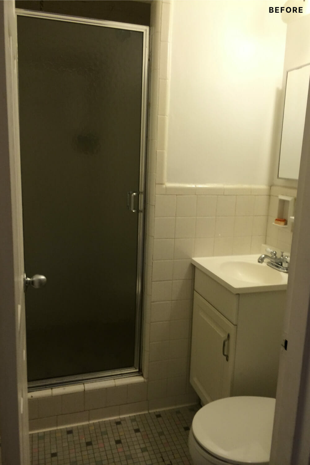 bathroom with single sink vanity and stand-in shower and white square tiles on half walls and toilet before renovation