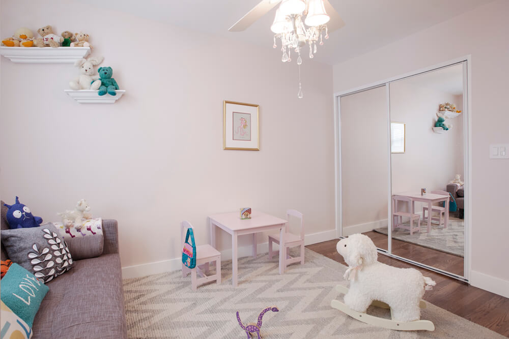kids playroom with hardwood floors and chandelier and mirrored closet with sliding doors after renovation