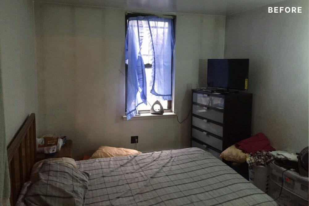 bedroom with a small window and dark wall paint and lacking natural lighting before renovation