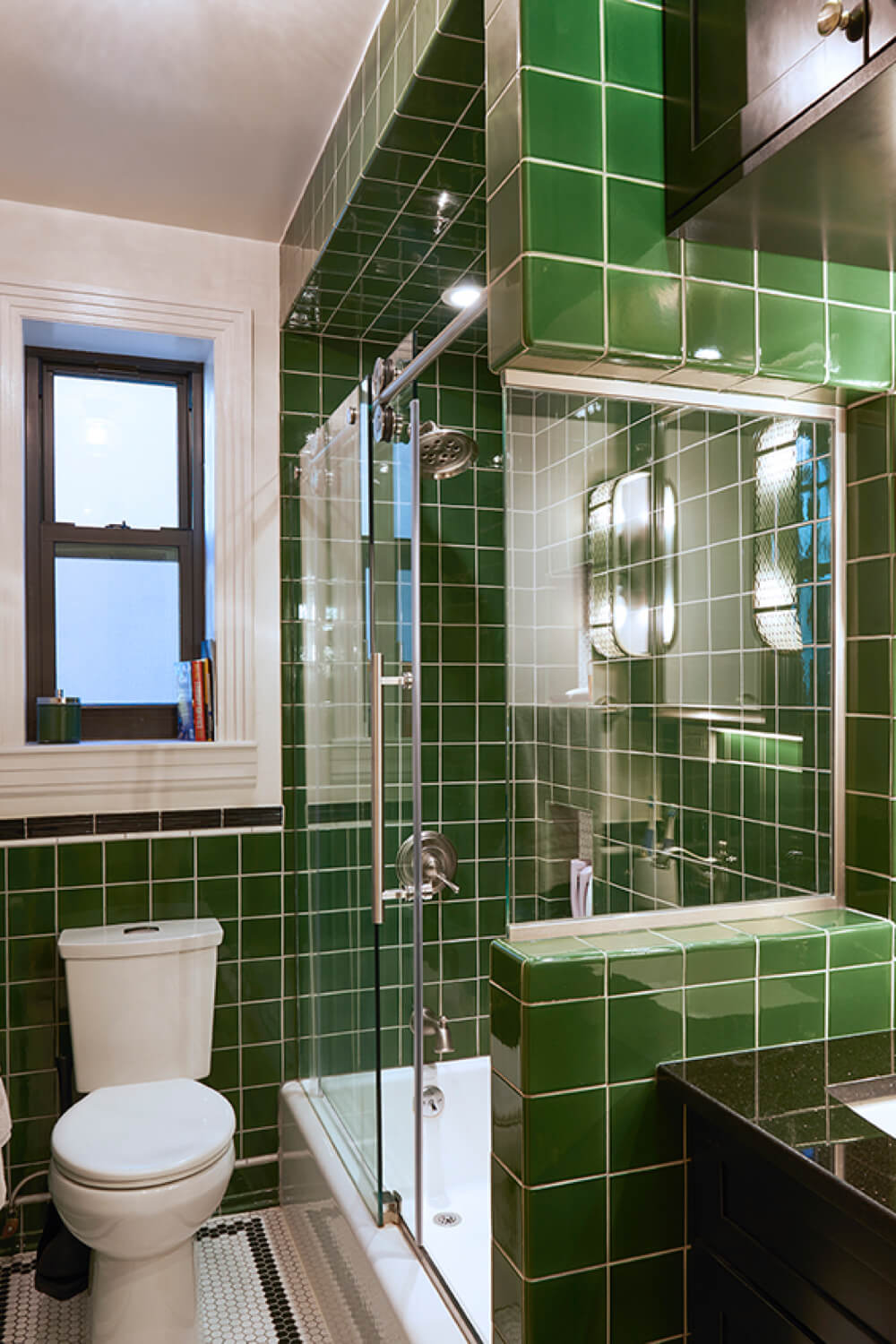 bathroom with dark green square wall tiles and walk in shower with glass dors and toilet after renovation