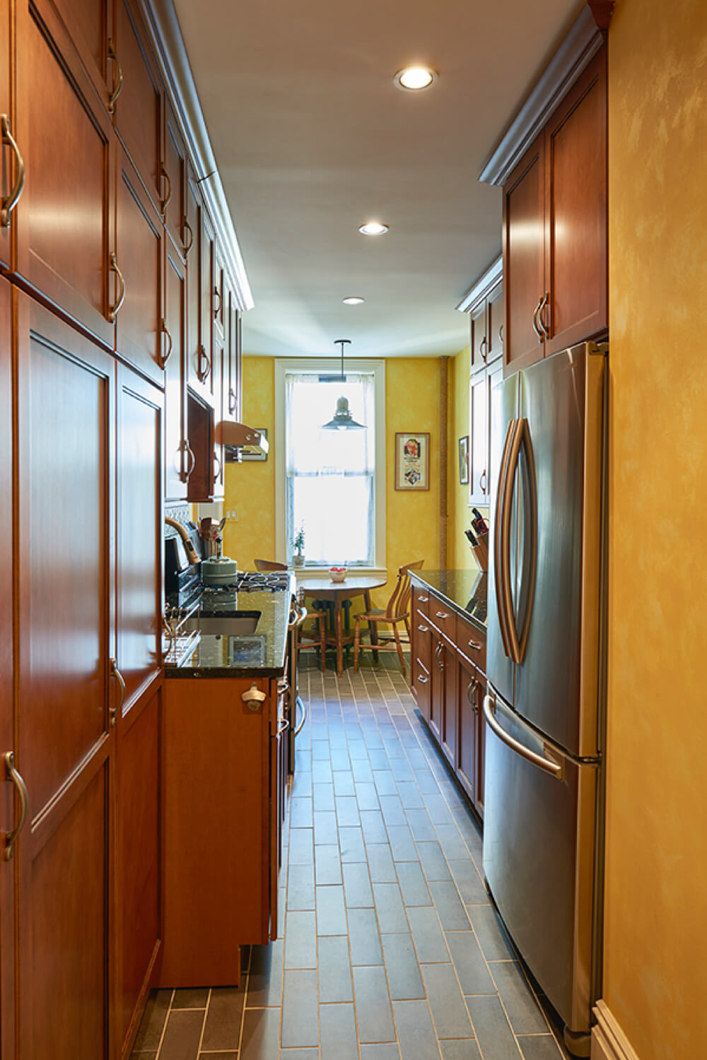narrow kitchen with black countertop and walnut cabinets and recessed lighting after renovation