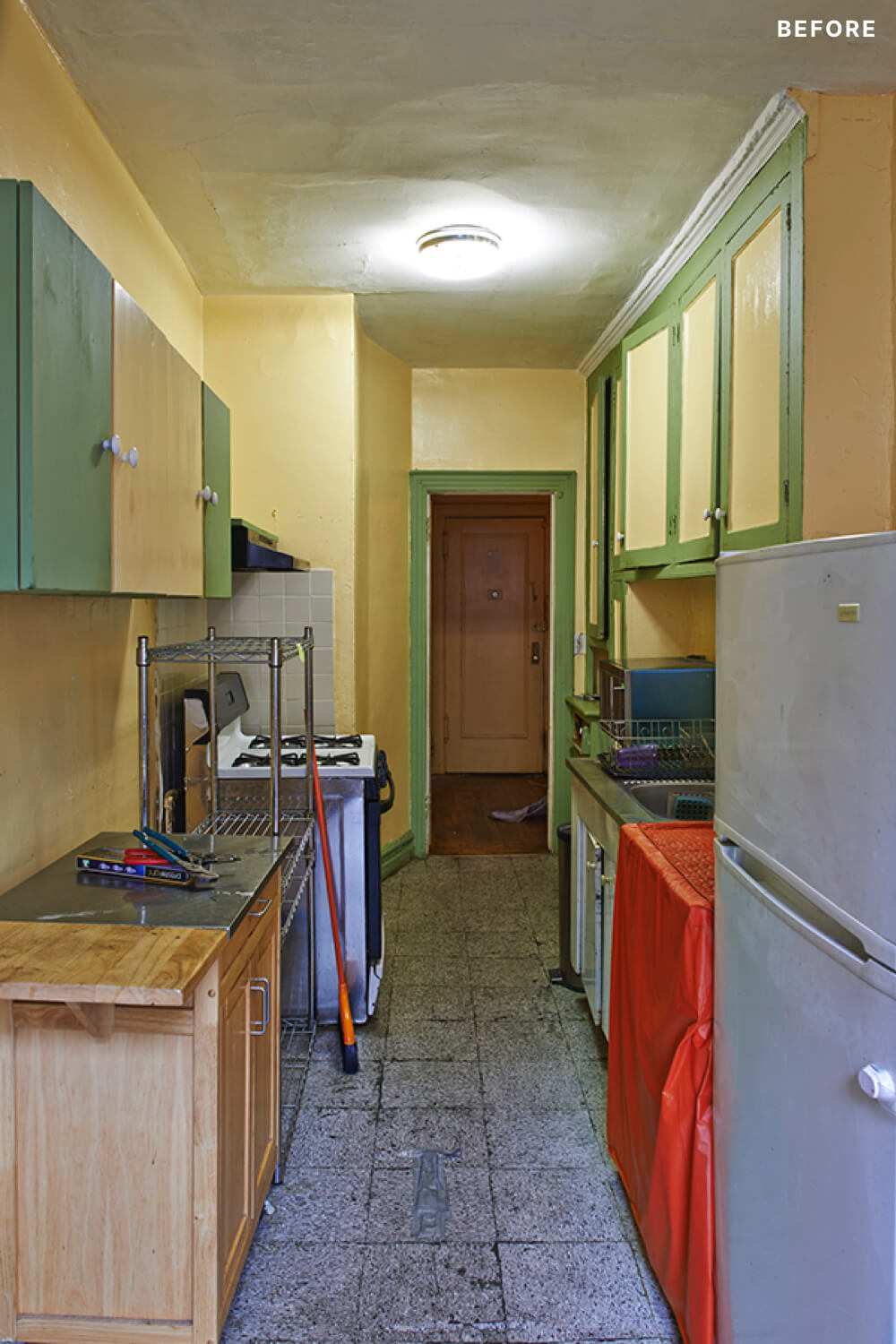 narrow kitchen with colored cabinets and flush mount ceiling light and gray floor tiles before renovation