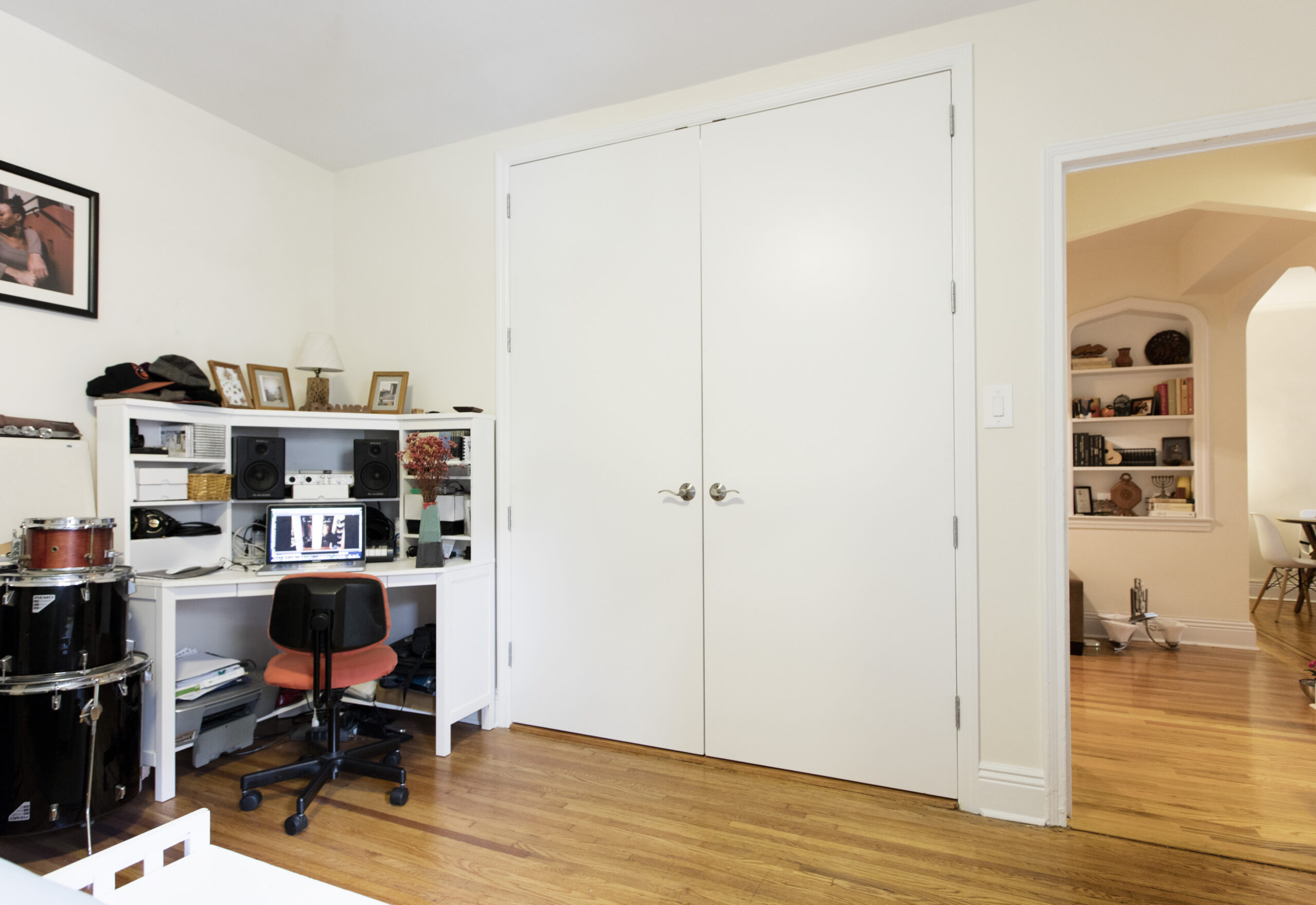 Bedroom workspace and double-door closet after a Ditmas Park apartment renovation, featuring a white desk and hardwood floors.
