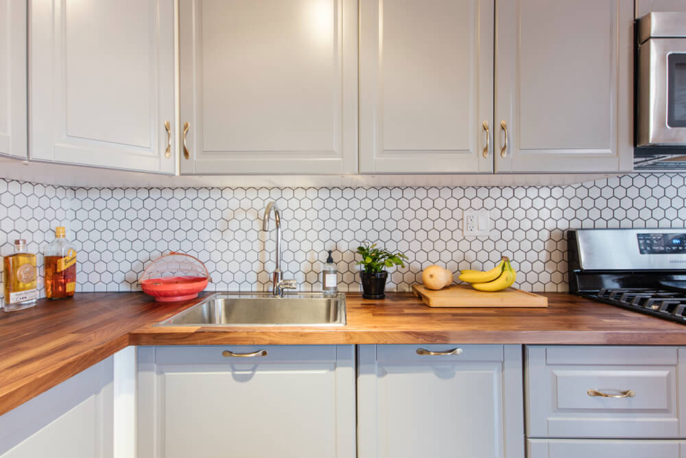 kitchen with butcher block countertop and off-white cabinets and honeycomb or hexagon back splash tiles after renovation
