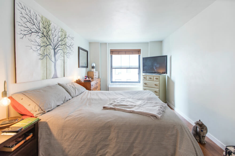 bedroom with white walls and hardwood floors and a window after renovation