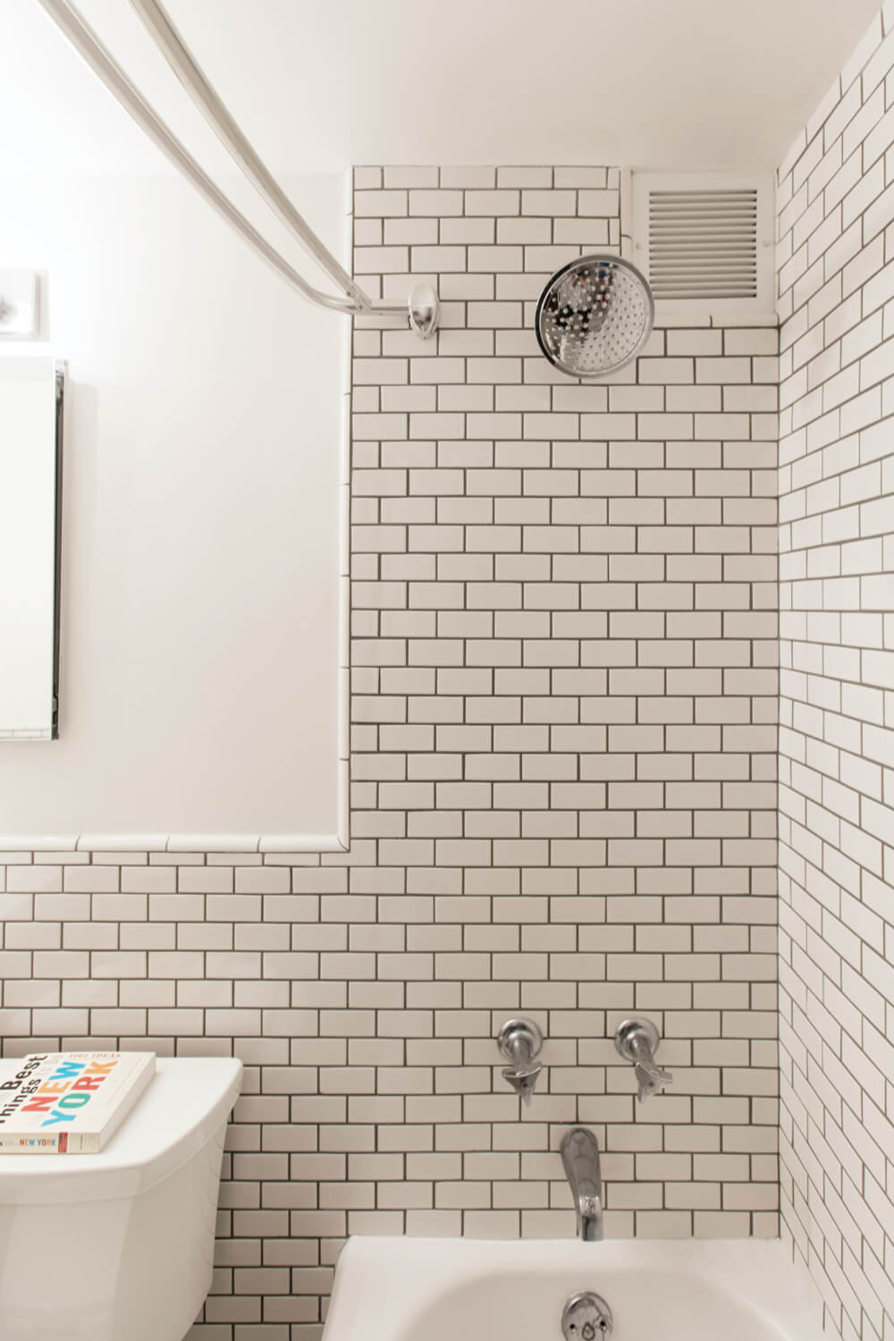 bathroom with bathtub and off white subway tiles on walls after renovation