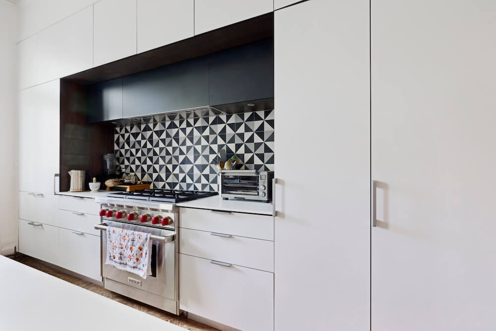 White open kitchen with cabinetry and abstract backsplash after renovation
