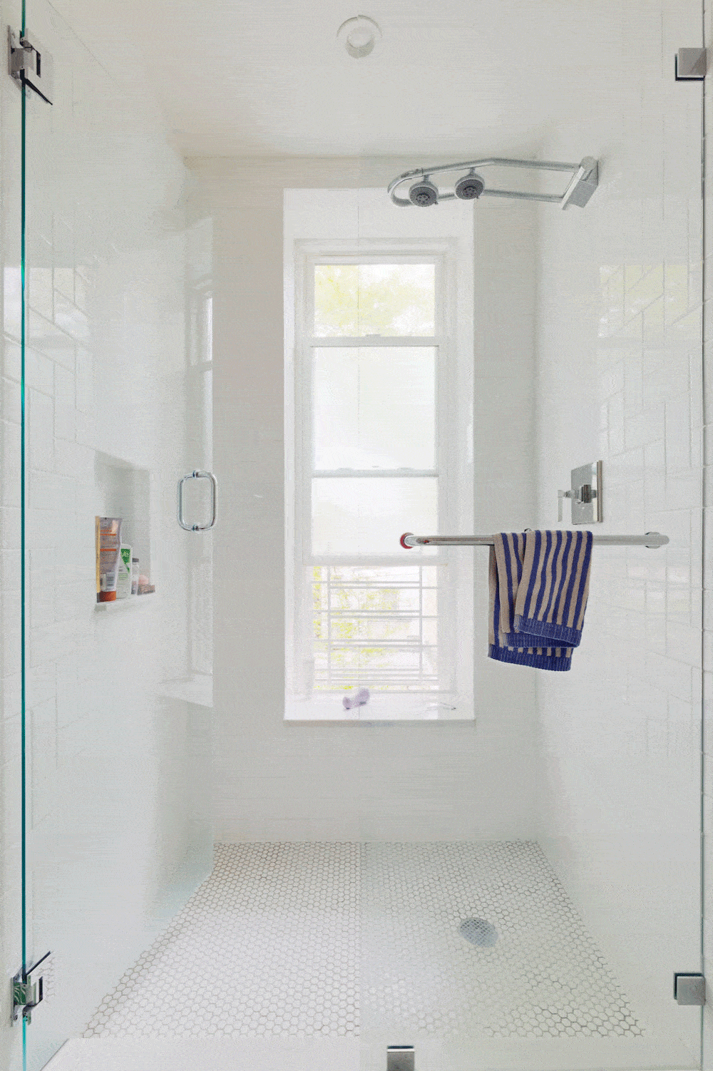 White walk in shower area with hung window and shower niche after renovation