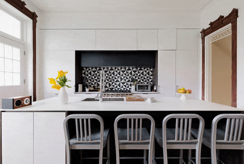 Black and white abstract backsplash tiles and large kitchen island with chairs after renovation