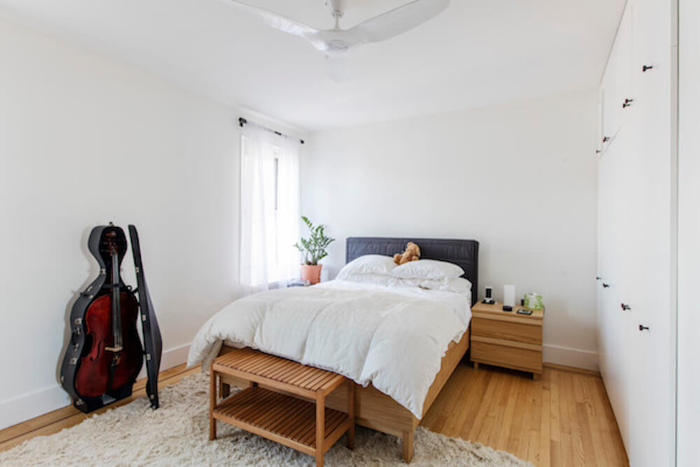 White bedroom with white wardrobe and view of musical instrument and shaggy rug after renovation