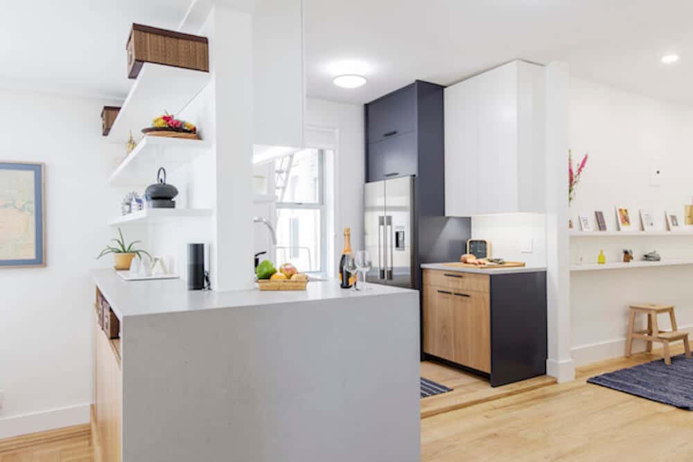 White unified countertop with open shelves and open kitchen with storage cabinets after renovation