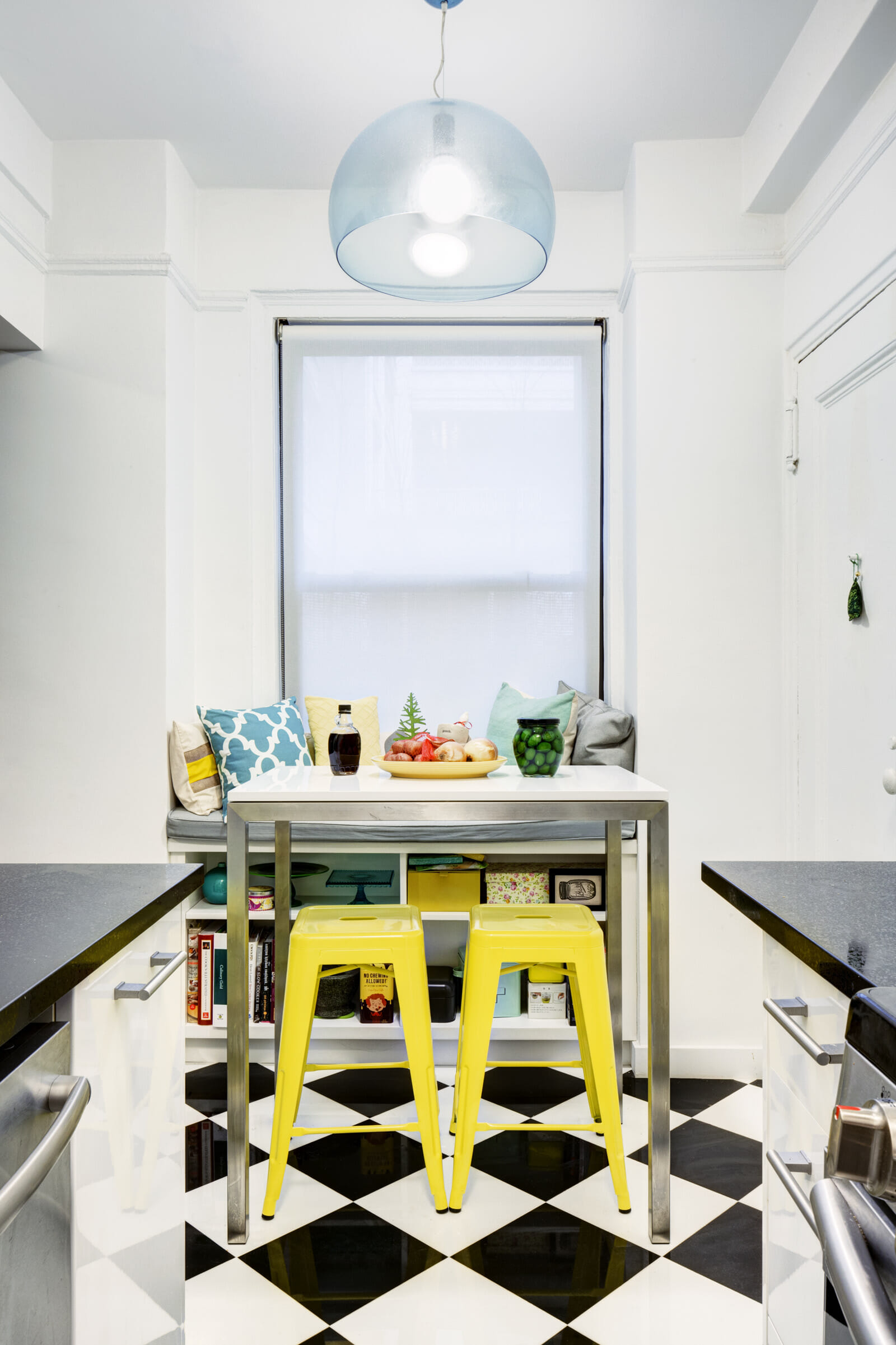 white and black galley kitchen with yellow stools
