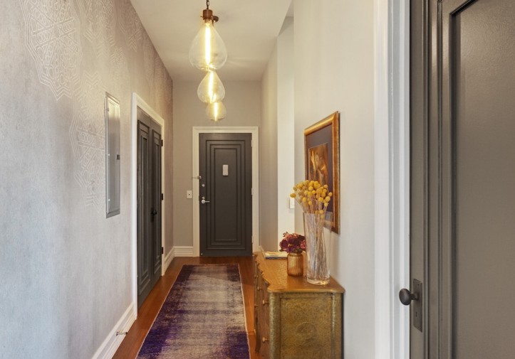 narrow white foyer with gray panelled doors and hanging accent lights after renovation