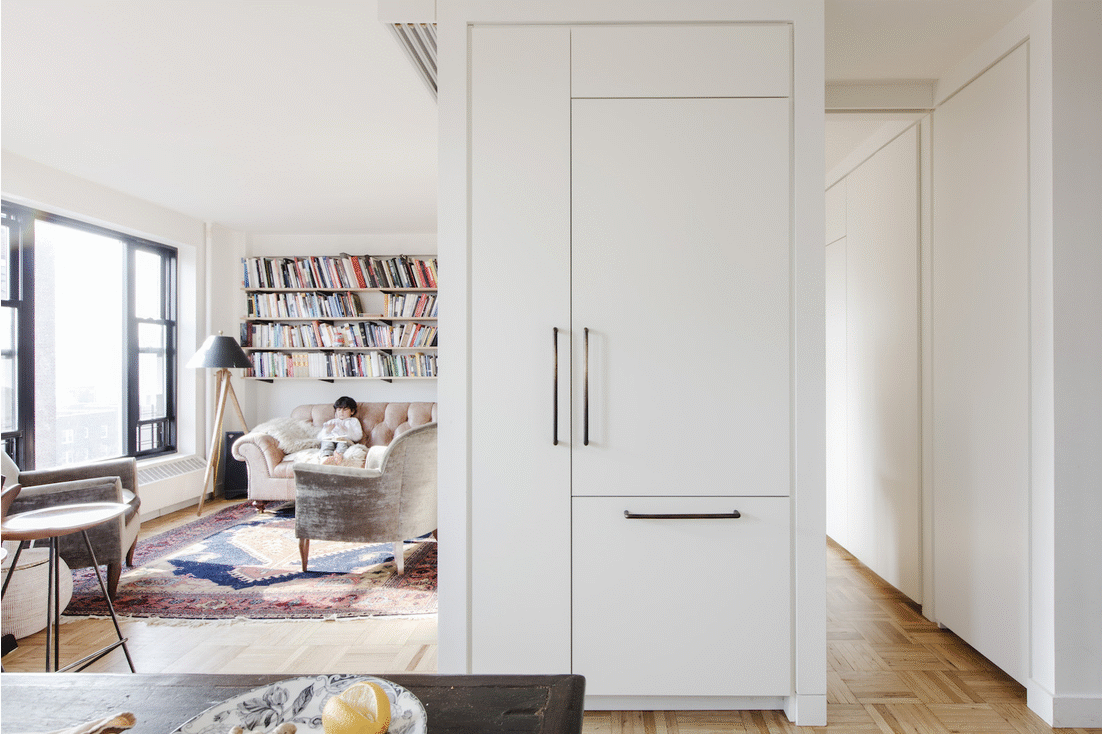 white long cabinets with long steel handles diving white living room with open book shelf after renovation