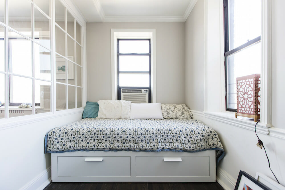 gray bed with storage with black double hung windows and white panelled room divider after renovation