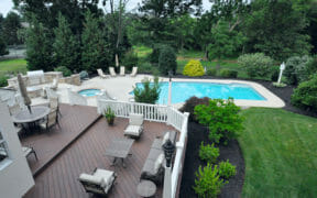 outdoor swimming pool and brown deck area with furniture after renovation
