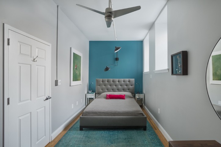 light gray small bedroom with single bed with blue highlight wall after renovation