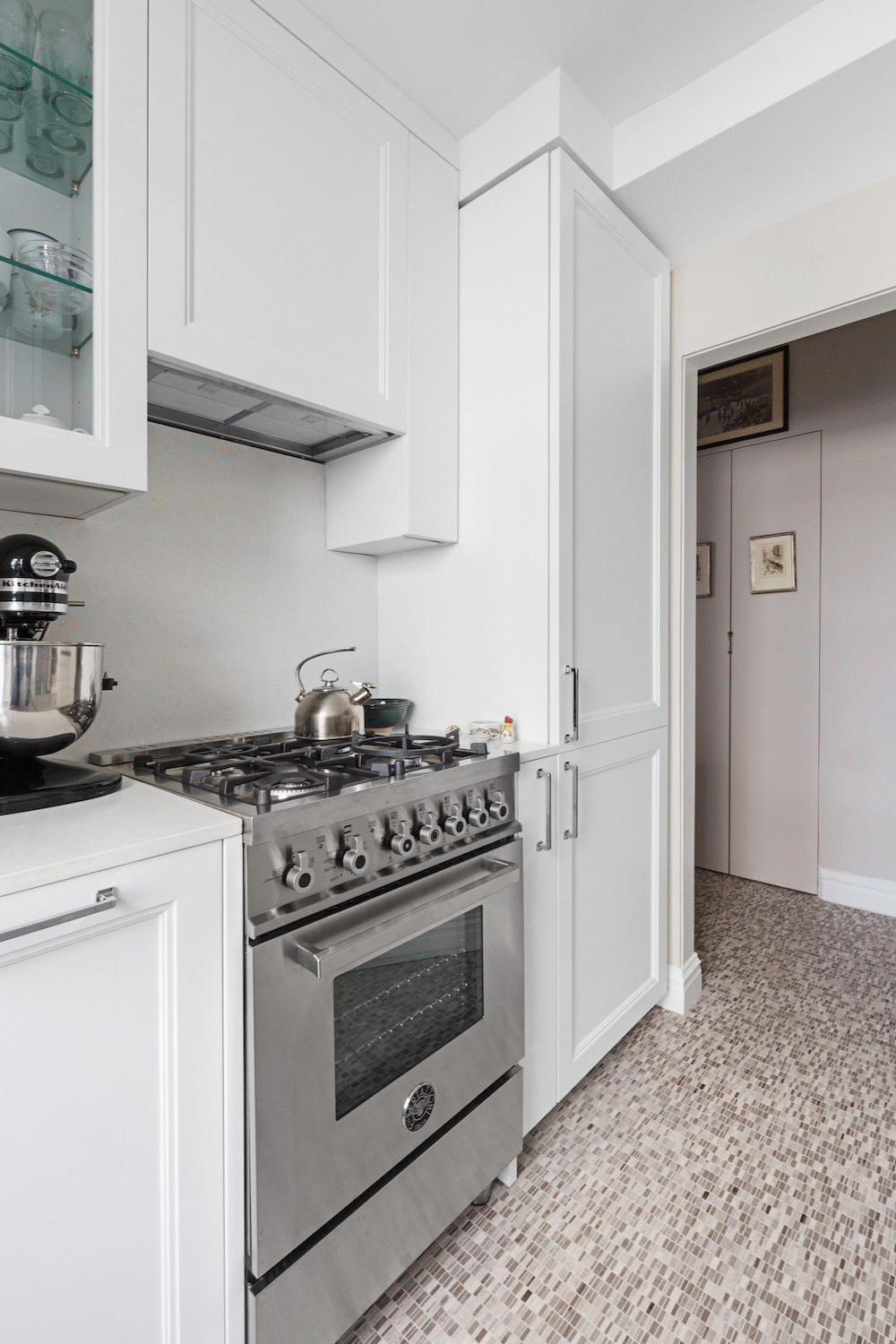 patterned floor in a small kitchen with white kitchen cabinets and cooking range after renovation