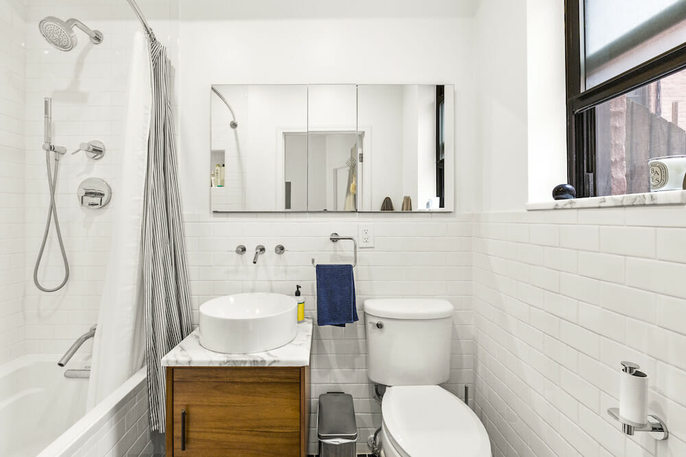 White bathroom with bathtub near the sink and the toilet near the windowsill after renovation