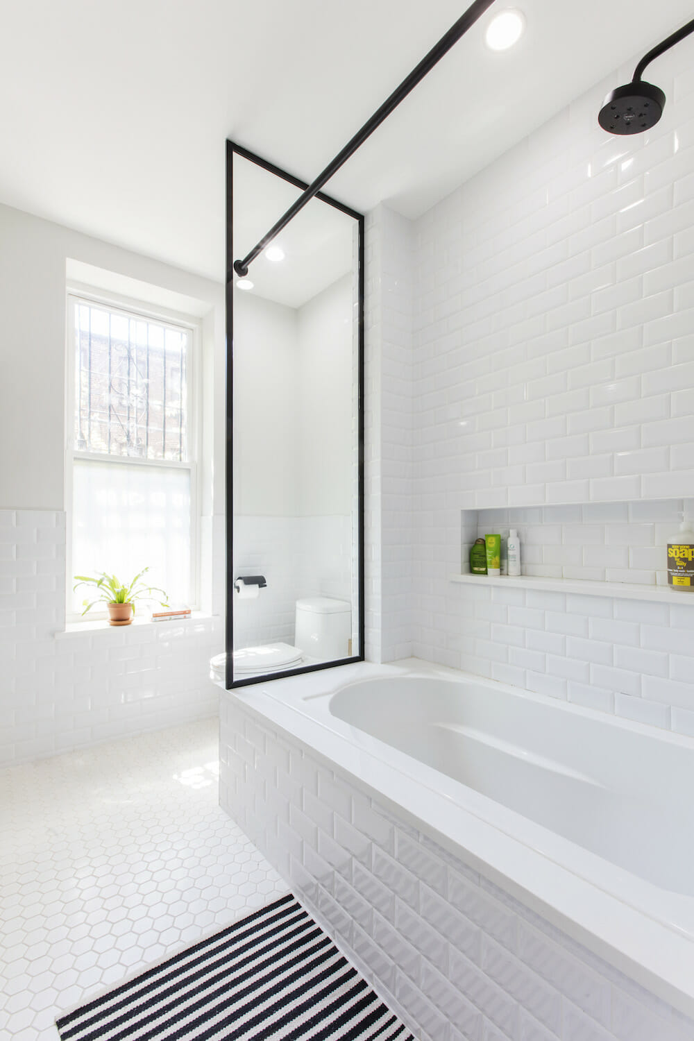 Image of a renovated bathroom with white subway tile and bathtub