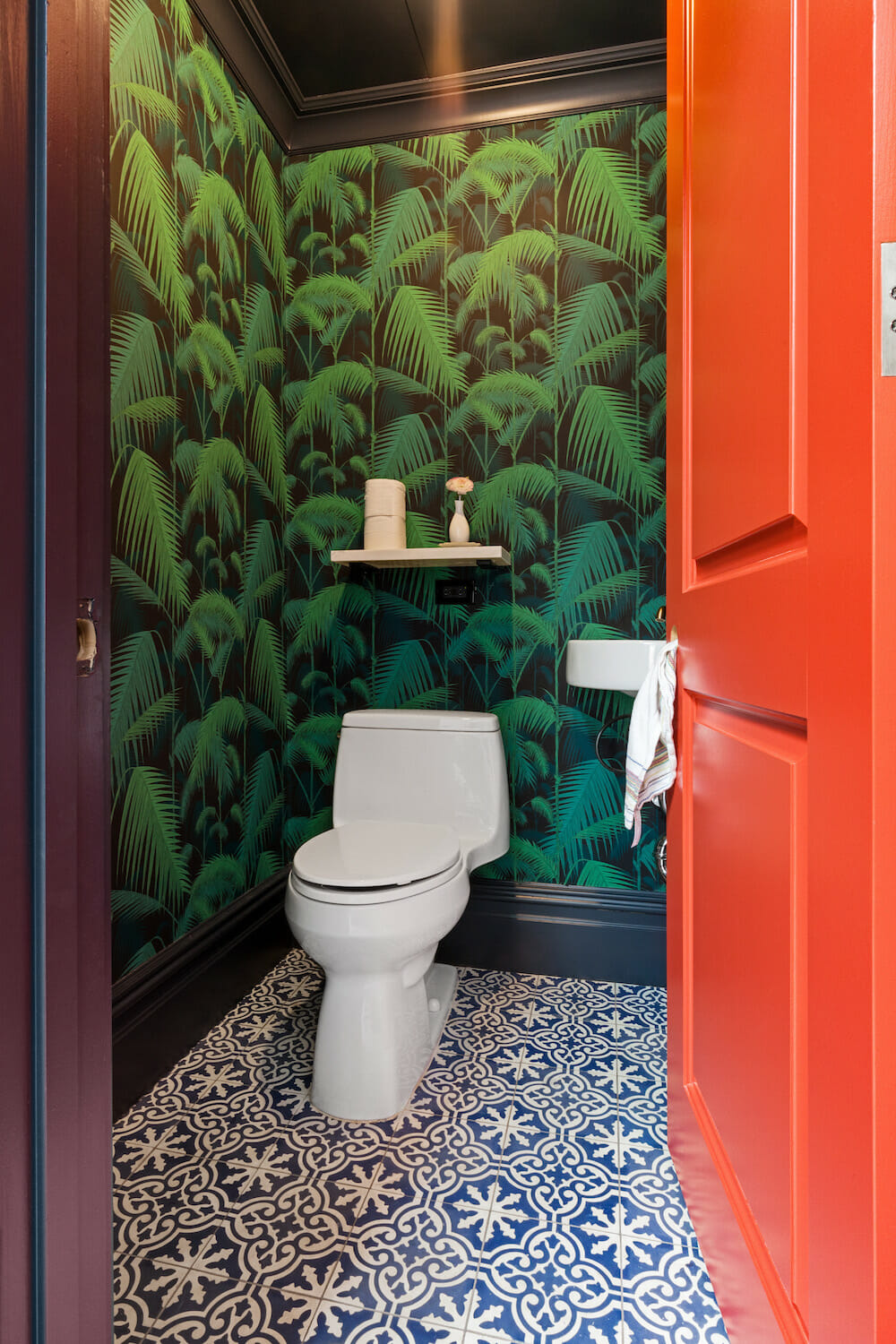 powder room with floral wallpaper orange door blue and white floor tile