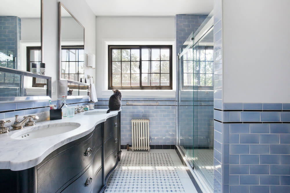 Blue and white bathroom with long double sink and glass shower door after renovation 