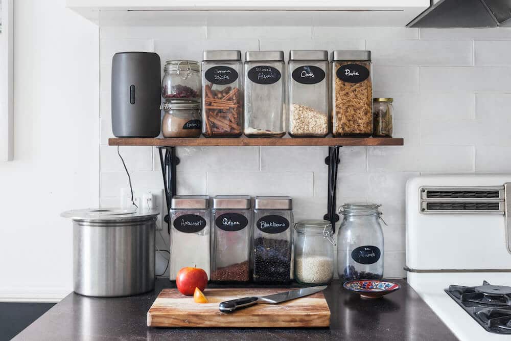 Wooden shelf holding glass jars and a granite countertop holding a chopping board after renovation