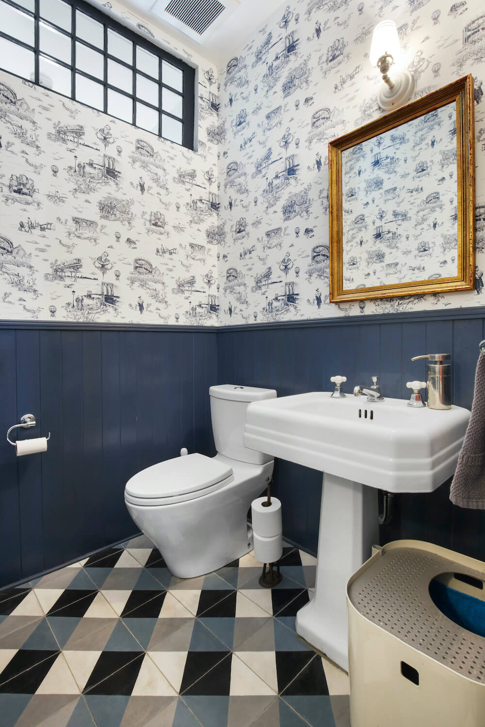 Blue powder room with pedestal sink and patterned wallpaper after renovation