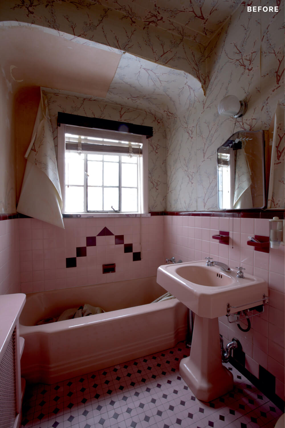 Pink bathroom with pink bathtub and pink pedestal along with pink wall paper before renovation