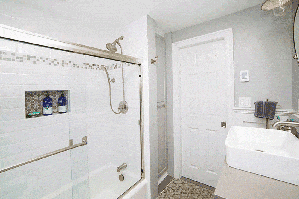 White bathroom with moveable shelved closet and glass shower space with built in shelves after renovation