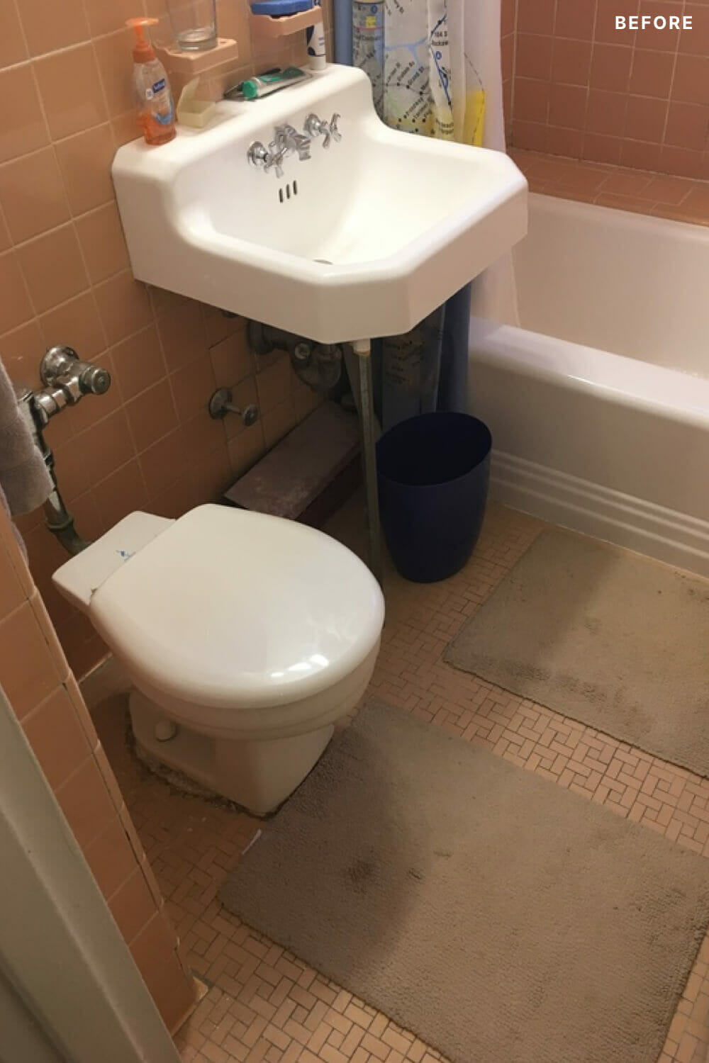 White pedestal sink with bathtub and toilet in an orange bathroom space before renovation