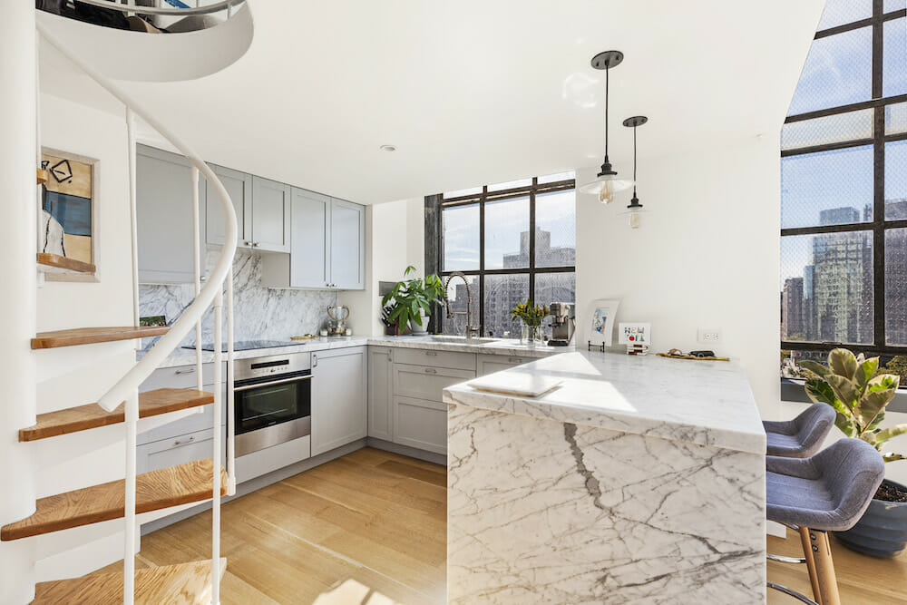 u-shaped kitchen with gray cabinets and marble waterfall peninsula